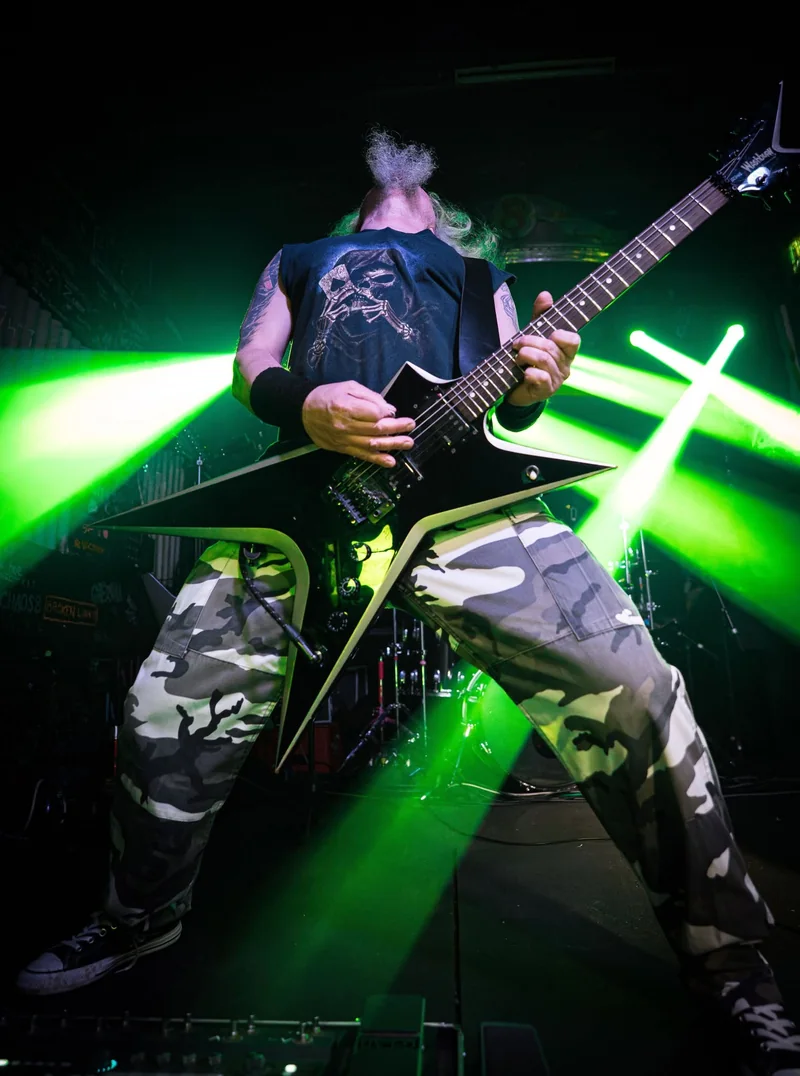 Ashborn guitarist playing under vivid green stage lights