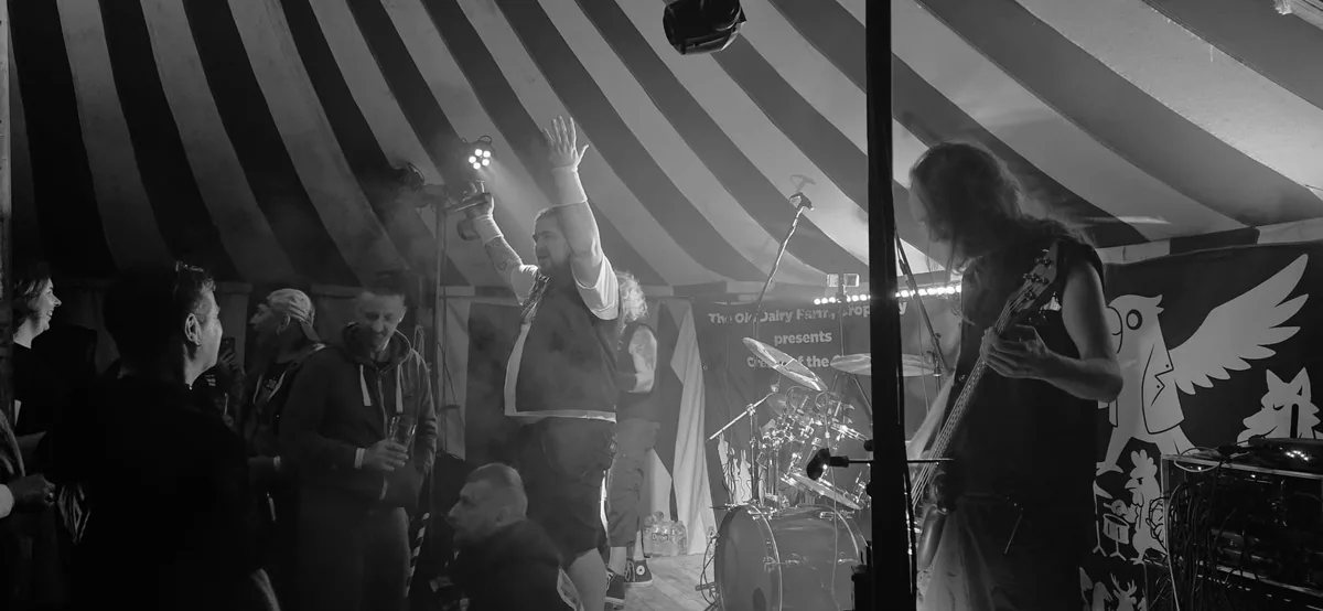 Ashborn performing on a tent stage in front of an audience, photographed in black and white